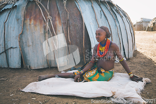 Image of Dasanesh woman resting in shadow of hut, Omorate, Omo Valley, Ethiopia