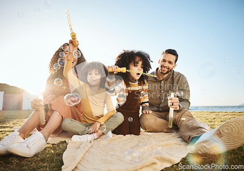 Image of Bubbles, game and children playing with parents, bonding and fun outdoor, relax on lawn with love and care. Mother, father and girl kids, people playful with liquid soap and summer in nature