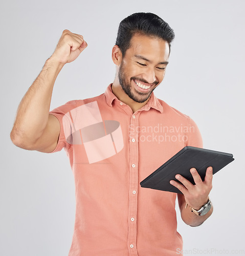 Image of Happy asian man, tablet and fist pump in winning, celebration or promotion against a white studio background. Excited male person with technology app in happiness for victory, success or good news