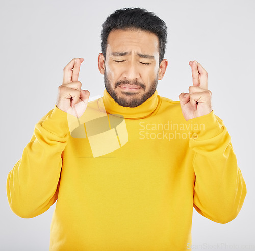 Image of Nervous, face and fingers crossed by asian man in studio with anxiety for news, feedback or review on grey background. Hand, emoji and Japanese guy with anxious for results, competition or giveaway