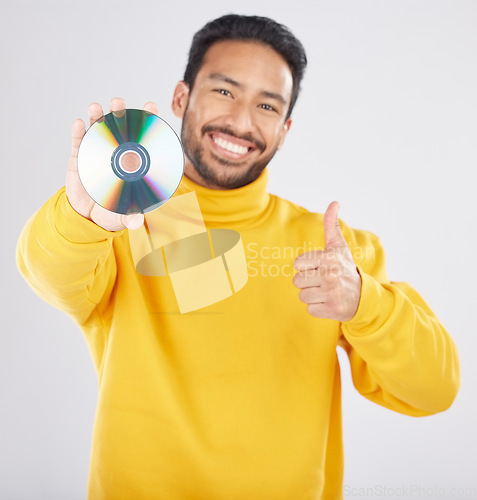 Image of Man, portrait and CD with thumbs up and happy from music of DVD in studio. Smile, motivation and like emoji hand sign of a male person with white background and holding multimedia disk of audio
