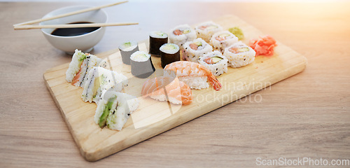 Image of Sushi, seafood and wood board, soy sauce and closeup, salmon and rice with avocado, healthy and luxury. Japanese cuisine, catering with lunch or dinner meal, chopsticks and food with nutrition