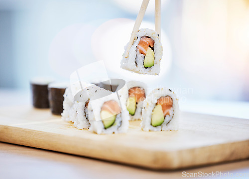 Image of Sushi, food on wood board with fish and eating, salmon and rice with avocado, healthy and luxury. Japanese cuisine, catering with lunch or dinner meal, chopsticks and seafood, nutrition and gourmet