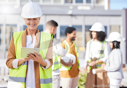 Image of Tablet, architecture and a senior woman construction worker on a building site with her team in the city. Technology, planning and safety with a female engineer reading a blueprint on the internet