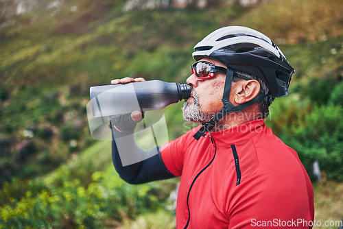 Image of Man, cyclist and drinking water on mountain in fitness, diet or natural nutrition in rest or break after cycling exercise. Thirsty male person with mineral drink for sustainability in cardio training