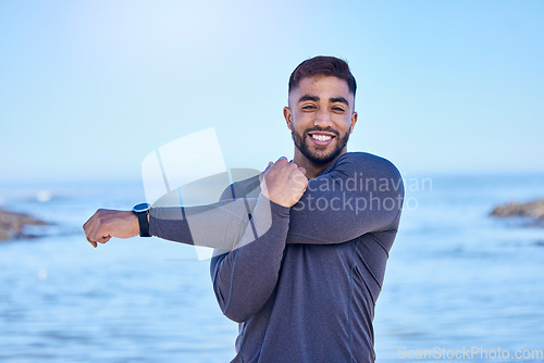 Image of Beach portrait, exercise and happy man stretching arm for outdoor freedom, sports workout or start routine. Blue sky, natural sea water and Indian person doing relax training warm up on nature island
