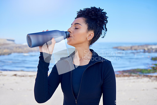 Image of Woman, fitness and drinking water by ocean for training, exercise and workout nutrition, health or wellness outdoor. Tired runner or african person with liquid bottle for energy, sports and cardio