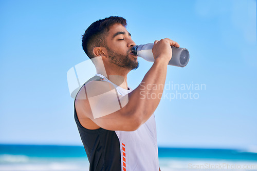 Image of Man, fitness and drinking water on beach in hydration after workout, training or outdoor exercise. Thirsty or sporty male person in healthy diet, natural nutrition or mineral in sustainability by sea