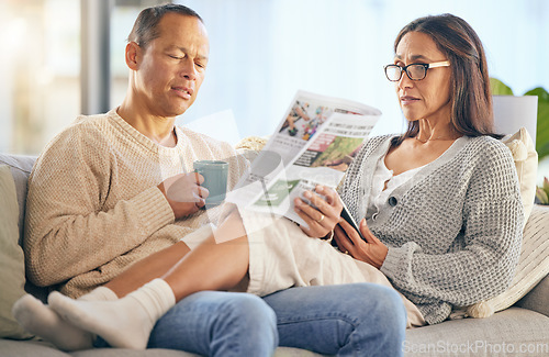 Image of Senior couple, newspaper and relax talking on sofa reading, morning conversation or quality time bonding together in living room. Elderly man, woman and news discussion, coffee and retirement peace