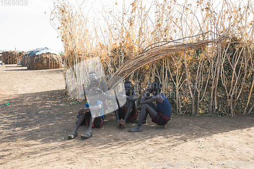 Image of Dasanesh woman resting in shadow of hut, Omorate, Omo Valley, Ethiopia