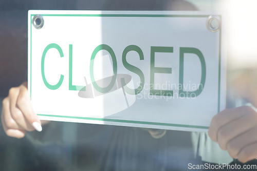 Image of Closed, sign and window with a small business owner or entrepreneur hanging a signage notice behind closed. Management, store and retail with a woman employee in a shop to hang a poster on a door