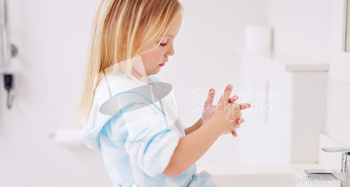 Image of Girl washing her hands in the bathroom of her home for hygiene, stop germs and prevent bacteria. Healthcare, clean and young child doing sanitary routine with soap and water in the basin at her house