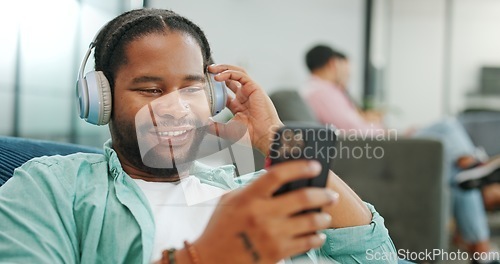 Image of Headphones, relax and black man with a phone on a sofa in living room listening to music and chatting. Rest, chill and African guy streaming radio, album or playlist while relaxing on couch at home.