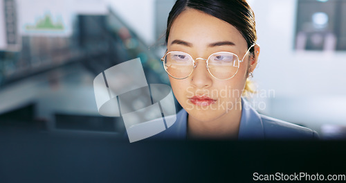 Image of Face, glasses and management with a business asian woman at work on a computer in her office. Data, reading and email with a young female employee working on a report using a desktop for research