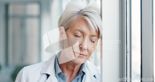Image of Doctor, sad and burnout of a senior healthcare employee at a window with depression about stress. Health consulting anxiety, headache and depressed feeling with mental health problem at a hospital