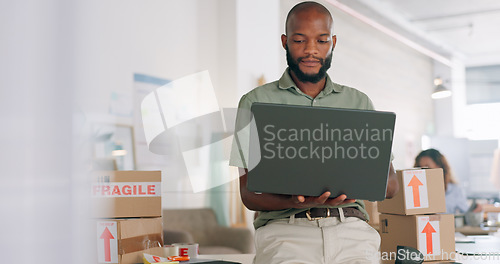 Image of Laptop, creative and online order with a black man designer working in a workshop for shipping or delivery. Computer, ecommerce and logistics with a male managing stock or the shipment of goods