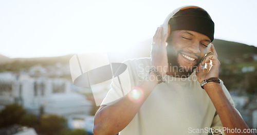 Image of Dance, music and man on a rooftop at sunset, dancing and streaming while listening to radio. Podcast, freedom and black man on balcony, positive and enjoy audio track on headphones with city view