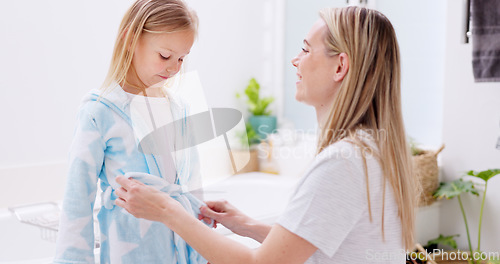 Image of Girl, mother and bathrobe in a bathroom for cleaning, wellness and hygiene in their home together. Children, washing and woman help child with gown after shower, bond and relax while talking