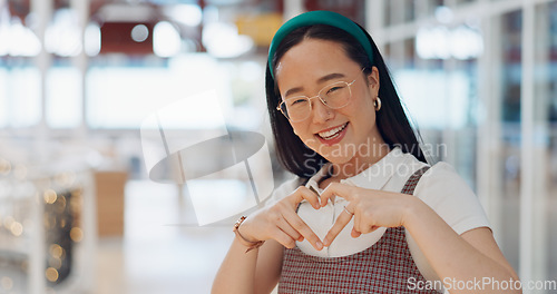 Image of Happy woman, heart and love for creative fashion style in a office with a smile and happiness with hands for support of announcement. Portrait of asian employee with emoji sign for marketing project