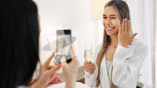 Image of Wedding, ring and engagement with a woman or bride taking a photograph on a phone and drinking champagne with a friend. Happy, smile and celebration with an attractive young female and her bridesmaid