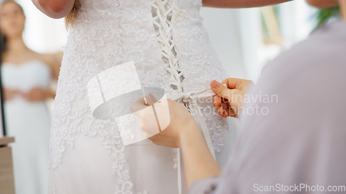 Image of Friends helping woman with wedding dress knot in a room or boutique for marriage ready, fitting or fashion with corset lace detail and hands. Bride with mirror reflection getting ready for love event