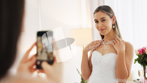 Image of Wedding, ring and engagement with a woman or bride taking a photograph on a phone and drinking champagne with a friend. Happy, smile and celebration with an attractive young female and her bridesmaid