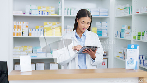 Image of Portrait of a cheerful and friendly pharmacist using a digital tablet to check inventory or online orders in a chemist. Young latino woman using pharma app to do research on medication in a pharmacy