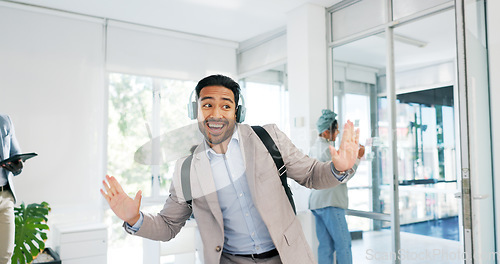 Image of Music, dance and motivation with a business man walking in an office while feeling positive or carefree. Success, happy or smile with a happy male employee arriving at work in headphones with a smile