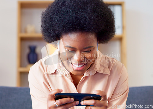 Image of Woman playing a mobile game on her phone in landscape mode in the lounge at home. Excited young gamer smiling and laughing while enjoying some fun online entertainment in leisure with gaming apps