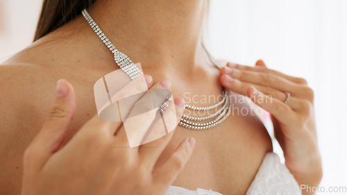 Image of Bride, jewelry and diamond necklace on a woman getting ready for her wedding day and touching her bridal jewelry while standing inside. Closeup neck of rich female wearing white dress and shiny bling
