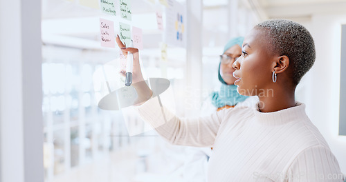 Image of Teamwork, business people and leadership of black woman with sticky note in office workplace. Coaching, collaboration and female employees brainstorming sales or marketing strategy on glass wall.