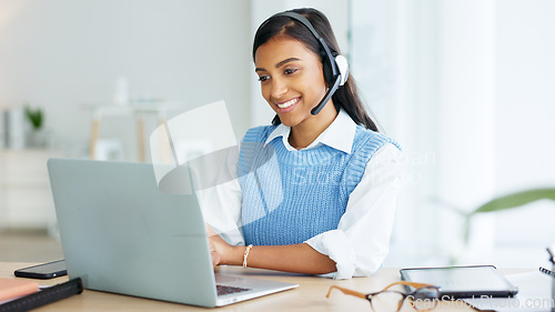 Image of Call center agent talking to clients while wearing a headset and answering their questions while typing on a laptop online. Helpline worker giving advice to people and helping them with problems