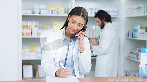 Image of Pharmacist woman answering the telephone and giving advice to customer on flu shot treatment options in pharmacy. Chemist assisting remote client by checking medicine stock on their computer database