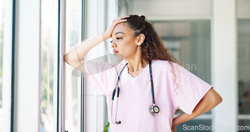 Image of Doctor, woman and stress by window with headache, burnout or sad in hospital workplace with hand on head. Black woman, healthcare medic and mental health problem at clinic job with anxiety in Atlanta