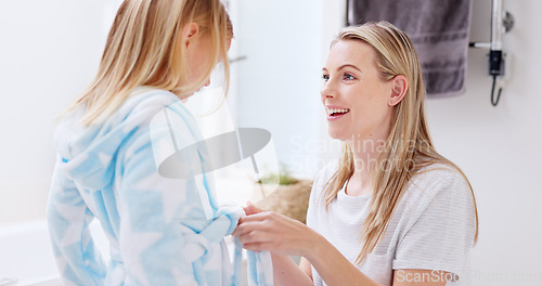 Image of Girl, mother and bathrobe in a bathroom for cleaning, wellness and hygiene in their home together. Children, washing and woman help child with gown after shower, bond and relax while talking