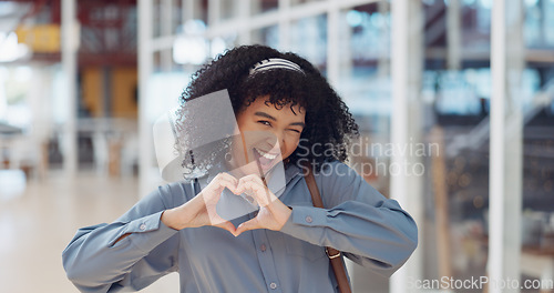 Image of Hands, heart and love with a business black woman making a hand gesture alone in her office at work. Happy, smile and positive with a female employee gesturing a hand sign for romance or affection