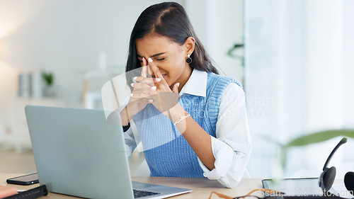 Image of An overworked business woman with a headache while working in her office. A tired or stressed corporate female in pain at the workplace. A young entrepreneur suffering from fatigue