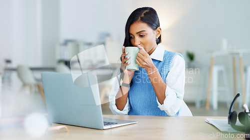 Image of Young business woman taking a coffee break after a completed task or meeting a deadline while working on a laptop at work. Pleased female corporate professional resting after sending sending an email