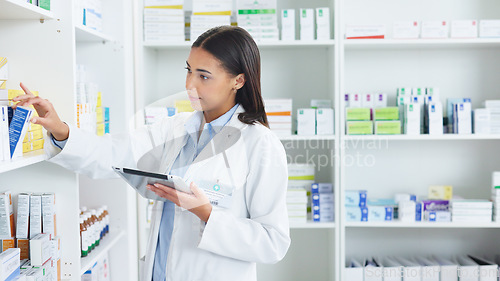 Image of A young female pharmacist stocktaking in a dispensary using a tablet. Doctor preparing prescriptions and medication at clinic or pharmacy. Healthcare professional sorting medicine with digital device