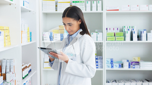 Image of A young female pharmacist stocktaking in a dispensary using a tablet. Doctor preparing prescriptions and medication at clinic or pharmacy. Healthcare professional sorting medicine with digital device