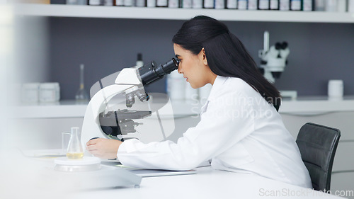Image of Young scientist using a digital tablet and microscope in a lab. Female pathologist analyzing medical samples while doing experiments to develop a cure. Microbiologist conducting forensic research