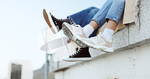 Image of Shoes, legs and couple on rooftop in the city sitting together, have fun and bonding. Fashion sneakers, style and friends kick feet on building edge, enjoy weekend, freedom and holiday in urban town