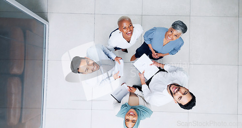 Image of Collaboration, overhead and huddle with a business team laughing while working together in an office. Face, teamwork and documents with a man and woman employee group standing in a circle from above