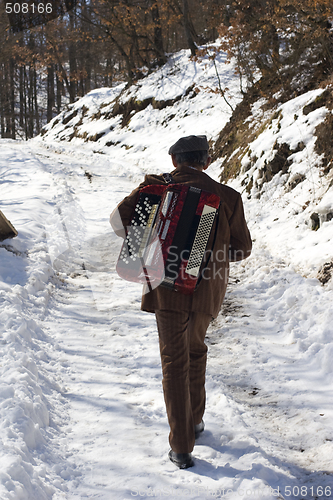 Image of man walking in the snow carrying his accordion