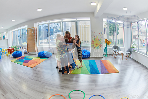 Image of A child hugging a teacher in a modern kindergarten