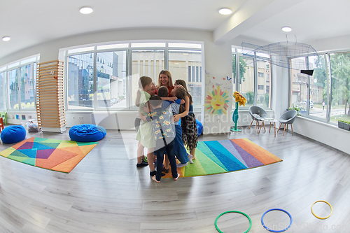 Image of A child hugging a teacher in a modern kindergarten