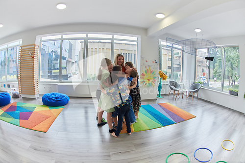 Image of A child hugging a teacher in a modern kindergarten