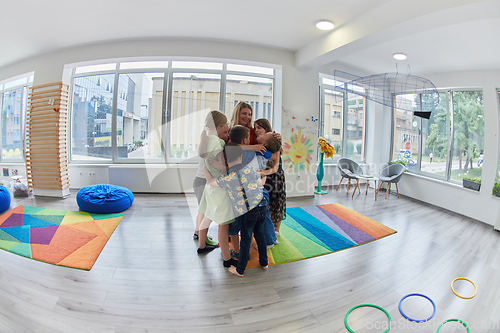 Image of A child hugging a teacher in a modern kindergarten