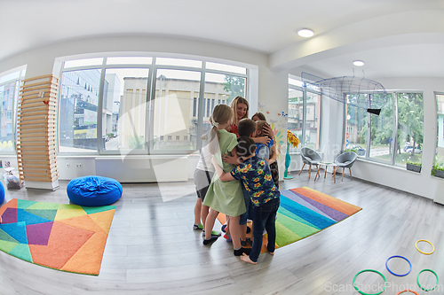 Image of A child hugging a teacher in a modern kindergarten