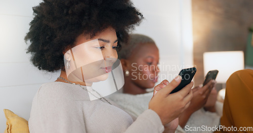 Image of Social media phone, home relax and friends in communication on mobile app, search the internet and smile for notification. African women on the living room sofa with mobile internet connection